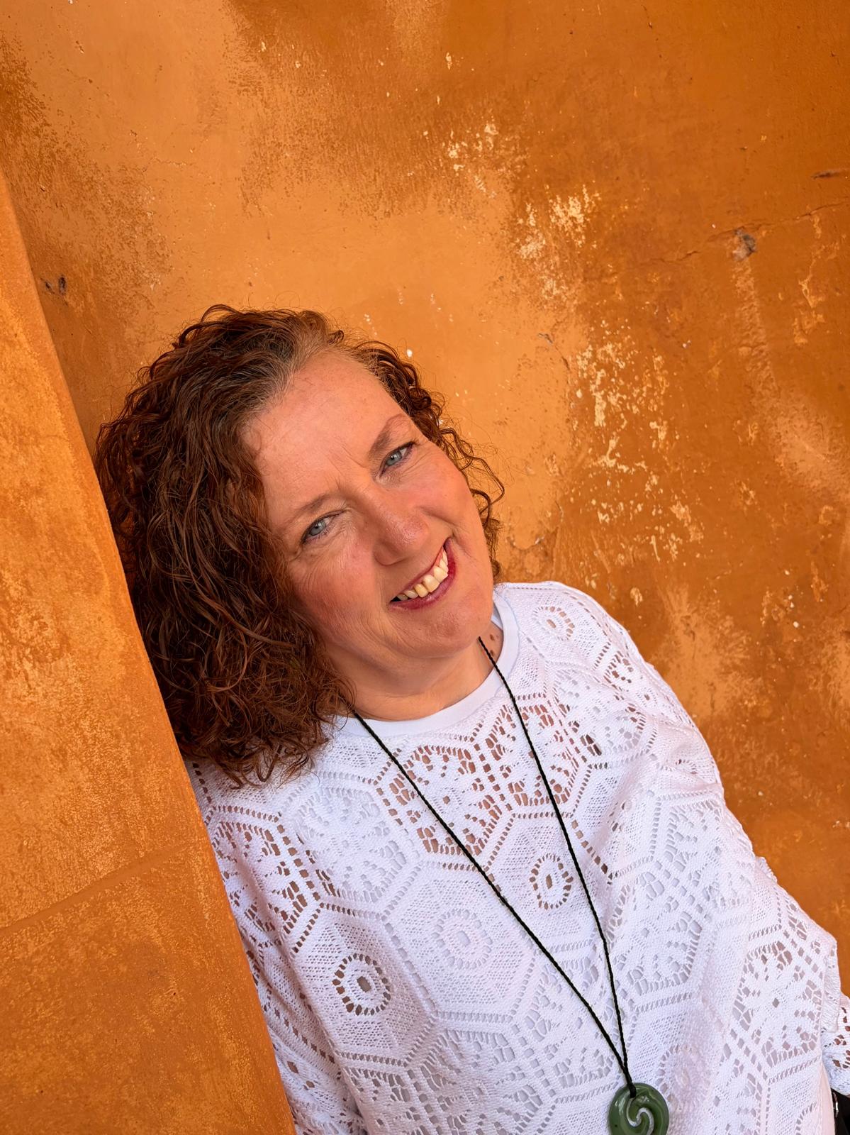Deirdre O’Donnell smiling, against a terracotta wall