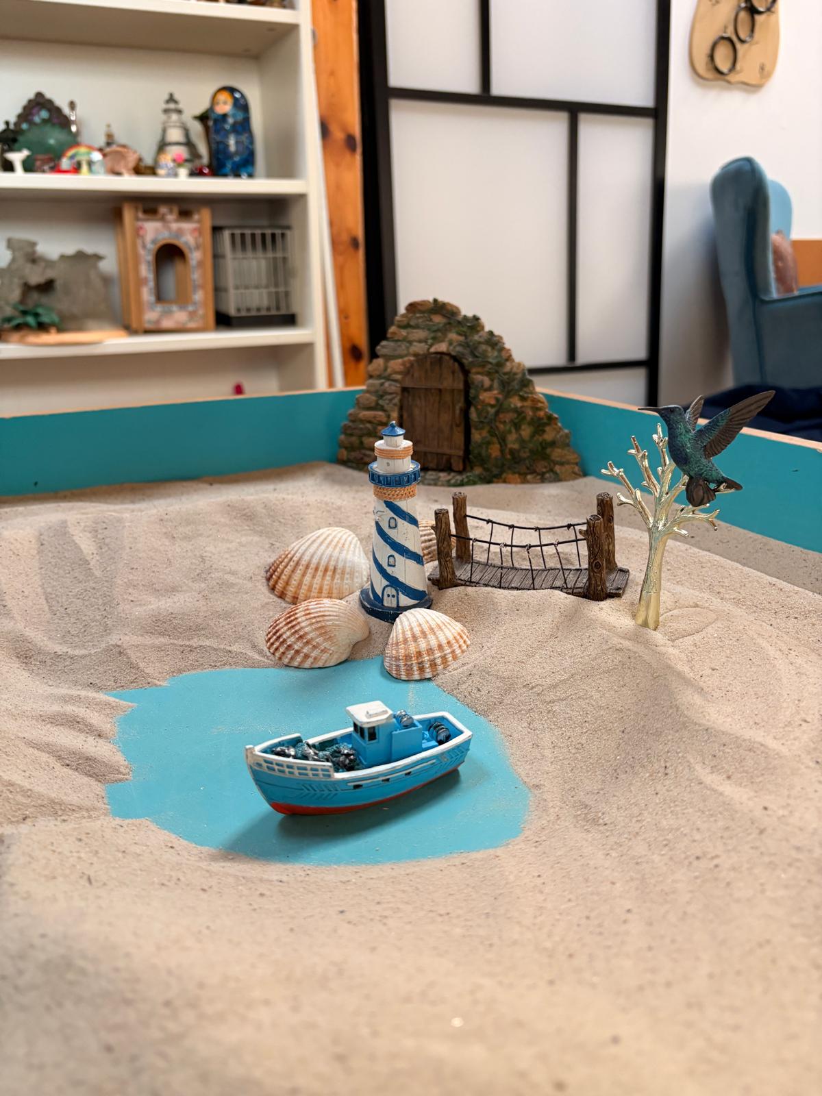 Shells, a lighthouse and a small boat arranged in a sandtray